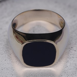 May include: A gold signet ring with a black onyx stone.