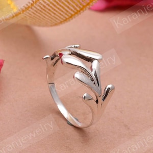 Op de afbeelding: Zilveren ring met een delicaat, bladerig ontwerp. De ring is open en verstelbaar om te passen op de meeste vingermaten.