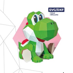 Puede incluir: Un modelo de papel de Yoshi verde y blanco, con detalles en rojo, sentado sobre una forma geométrica rosa. El modelo está hecho de 54 piezas y mide 23 x 23 x 25 cm. La imagen incluye el texto "YOSHI" y "SVG/DXF".
