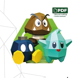 Puede incluir: Un PDF de papercraft con tres figuras geométricas: un Goomba marrón, un Bob-omb azul y un Luma turquesa. Dimensiones: 14 cm x 13 cm x 13 cm. Incluye el texto "BOMBA, GOOMBA Y LUMA" y "Corte manual".