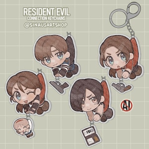 May include: Four Resident Evil connection keychains with chibi character designs. Each keychain has a different character design, with a silver clasp at the top. The text "RESIDENT EVIL CONNECTION KEYCHAINS @SINAUSARTSHOP" is at the top.