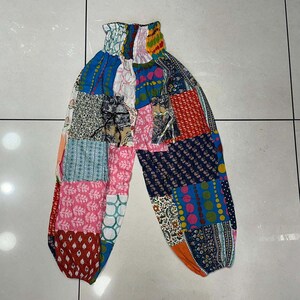 May include: Patchwork pants with a colorful design featuring pink, blue, red, and green. The pants have a wide leg and a comfortable elastic waistband.