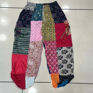 Può includere: Pantaloni patchwork con una varietà di colori e motivi, tra cui verde, blu, rosso e rosa. I pantaloni hanno una vita con coulisse e una vestibilità ampia.