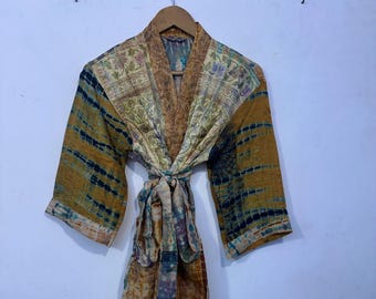 May include: A patterned kimono robe with a tie closure. The robe features a mix of floral and abstract designs in shades of gold, blue, and brown. The sleeves are three-quarter length, and the robe is hanging on a wooden hanger.