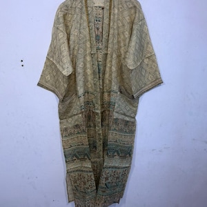 May include: A long-sleeved, open-front kimono robe featuring a light beige base with a repeating geometric diamond pattern on the upper section and a contrasting horizontal band of intricate floral and tribal motifs in shades of green and brown.