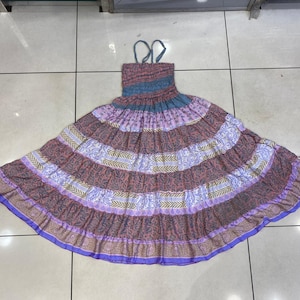 May include: A multi-colored maxi dress with a floral print and a tiered skirt. The dress has a blue and purple color scheme with a light pink and white floral pattern.