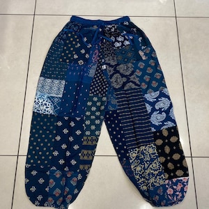 May include: Blue patchwork trousers with a variety of floral and geometric patterns. The trousers have an elastic waistband and a drawstring.