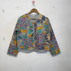 Pode incluir: Casaco acolchoado com um design de patchwork colorido com leopardos amarelos, motivos florais turquesa e vermelhos e fundos cinzentos e azuis. O casaco tem decote em V e é forrado com um tecido listrado.
