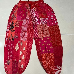 Pode incluir: Calças vermelhas de patchwork com cintura de cordão. As calças são feitas de uma variedade de tecidos com padrões diferentes, incluindo floral, geométrico e paisley.