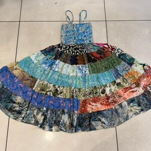Puede incluir: Un vestido de verano patchwork con un corpi&ntilde;o azul con estampado floral y tirantes finos. La falda es una vibrante mezcla de parches de tela coloridos en varios patrones y tonos, incluyendo azules, verdes, naranjas y rosas. El vestido est&aacute; dise&ntilde;ado para un ajuste relajado.