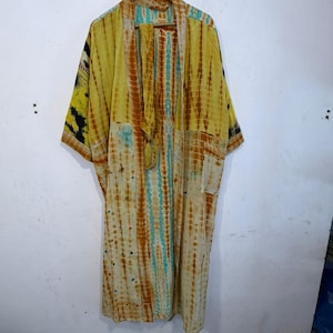 May include: A long, open-front kimono robe featuring a tie-dye pattern in shades of yellow, orange, and turquoise. The garment has wide, three-quarter length sleeves and a matching fabric belt, with a distinct black and yellow patterned panel on the sleeve.