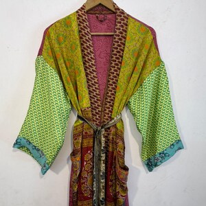 May include: A colorful, patterned robe with long sleeves and a belt. The robe features a mix of green, red, and purple fabrics with various designs. The sleeves have a green geometric pattern, and the robe has two pockets.