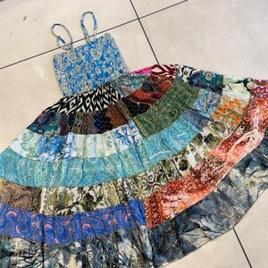 Puede incluir: Un vestido largo patchwork con corpi&ntilde;o azul y tirantes finos. La falda presenta una variedad de telas estampadas en tonos de azul, verde, naranja y rosa. El vestido est&aacute; dise&ntilde;ado para un ajuste relajado.