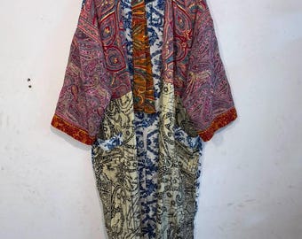 May include: A long-sleeved kimono-style robe featuring a patchwork design with various patterns. The upper section displays a pink and red paisley print, while the lower portion features a cream and black intricate scrollwork pattern.