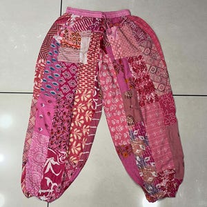 May include: Pink patchwork pants with a floral pattern. The pants are made of a soft, lightweight fabric and have a comfortable fit.