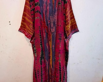 May include: A long-sleeved kimono-style robe featuring a vibrant tie-dye pattern in shades of magenta, deep purple, black, and golden yellow. The garment has an open front design with a matching fabric tie belt and wide, loose-fitting sleeves.