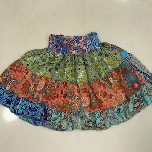 May include: A multi-colored patchwork skirt with a floral pattern. The skirt has a gathered elastic waistband and is made of a soft, lightweight fabric.