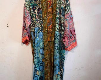 May include: A long-sleeved kimono robe featuring a patchwork design with various colorful patterns including paisley, floral, and abstract motifs in shades of blue, green, orange, and pink, with a central panel of brown and gold paisley print.