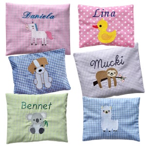 Könnte beinhalten: Fünf personalisierte Kissenbezüge mit verschiedenen Tiermotiven. Die Kissen sind aus Gingham-Stoff mit einem weißen und blauen Muster. Die Namen auf den Kissen sind Daniela, Lina, Mucki, Bennet und ein Name, der auf dem Bild nicht sichtbar ist.