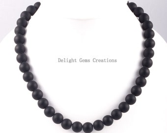 Puede incluir: Un collar de cuentas negras hecho de cuentas redondas con acabado mate. El collar está sobre un fondo blanco. Delight Gems Creations está escrito en el centro de la imagen.