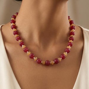 May include: A beaded necklace featuring alternating red and light yellow beads. The necklace is composed of round, polished beads, creating a striking contrast in color and texture. The necklace is a piece of jewelry.