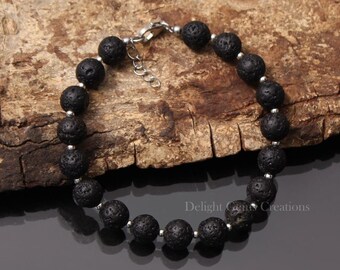 May include: Black lava rock bead bracelet with a silver clasp. The bracelet is made of natural lava rock beads and is approximately 7 inches in length.