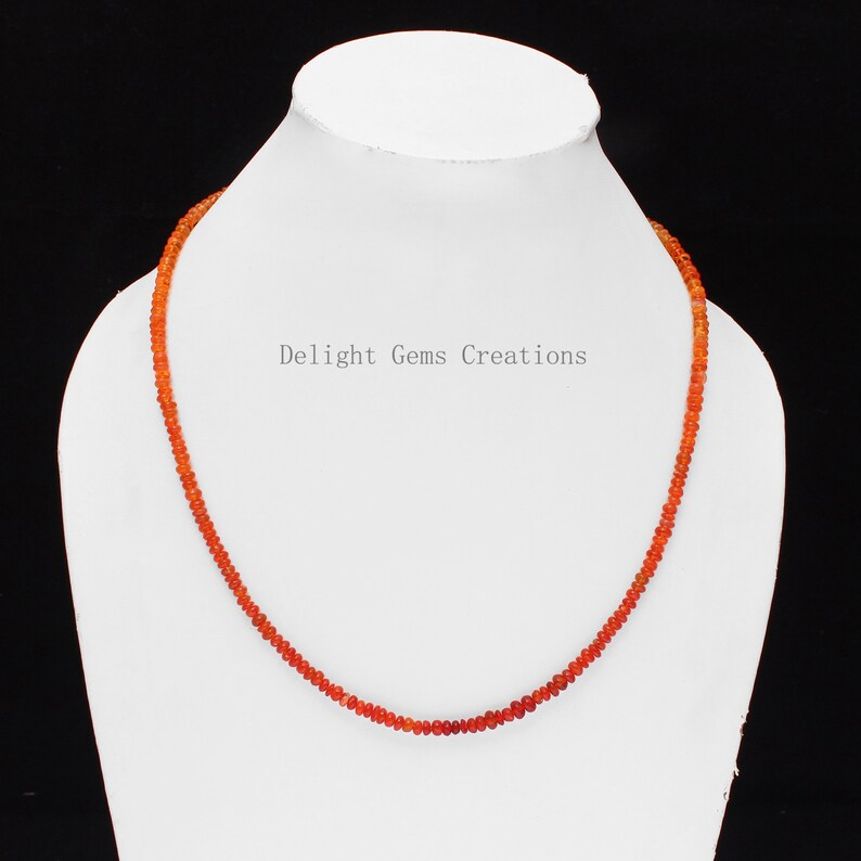 May include: A necklace made of small, round, orange carnelian beads. The necklace is displayed on a white mannequin bust. The text "Delight Gems Creations" is visible on the bust.
