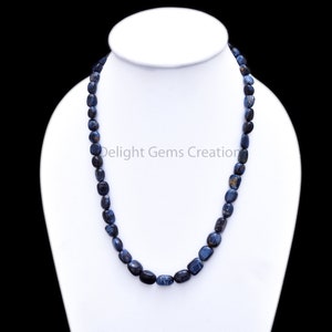 May include: A blue and black gemstone necklace made of smooth, oval-shaped beads. The necklace is approximately 18 inches long and is displayed on a white mannequin.