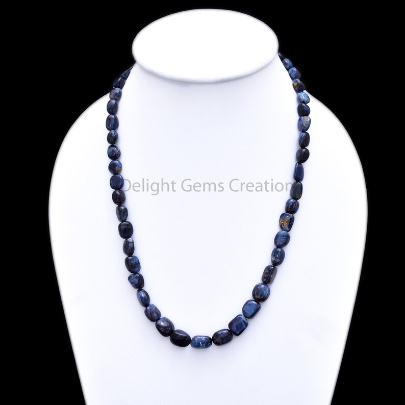 May include: A blue and black gemstone necklace made of smooth, oval-shaped beads. The necklace is approximately 18 inches long and is displayed on a white mannequin.