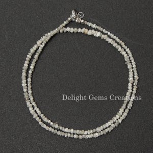 May include: A double strand necklace made of small, rough, white diamonds. The necklace is strung on a silver chain and has a silver clasp.