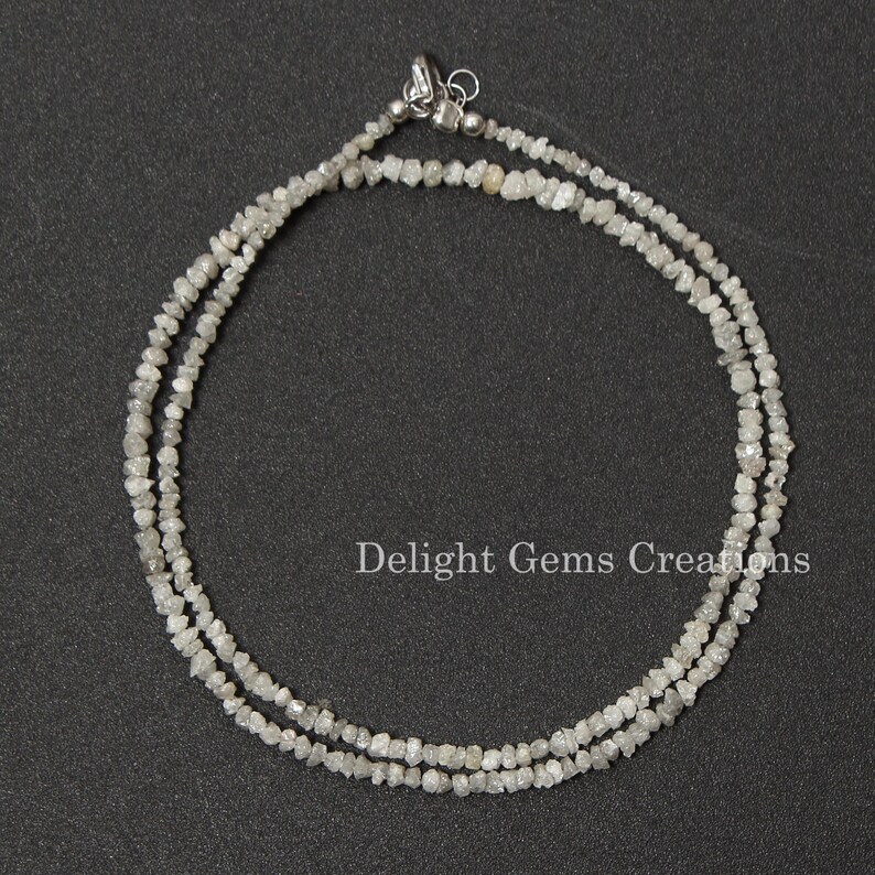 May include: A double strand necklace made of small, rough, white diamonds. The necklace is strung on a silver chain and has a silver clasp.