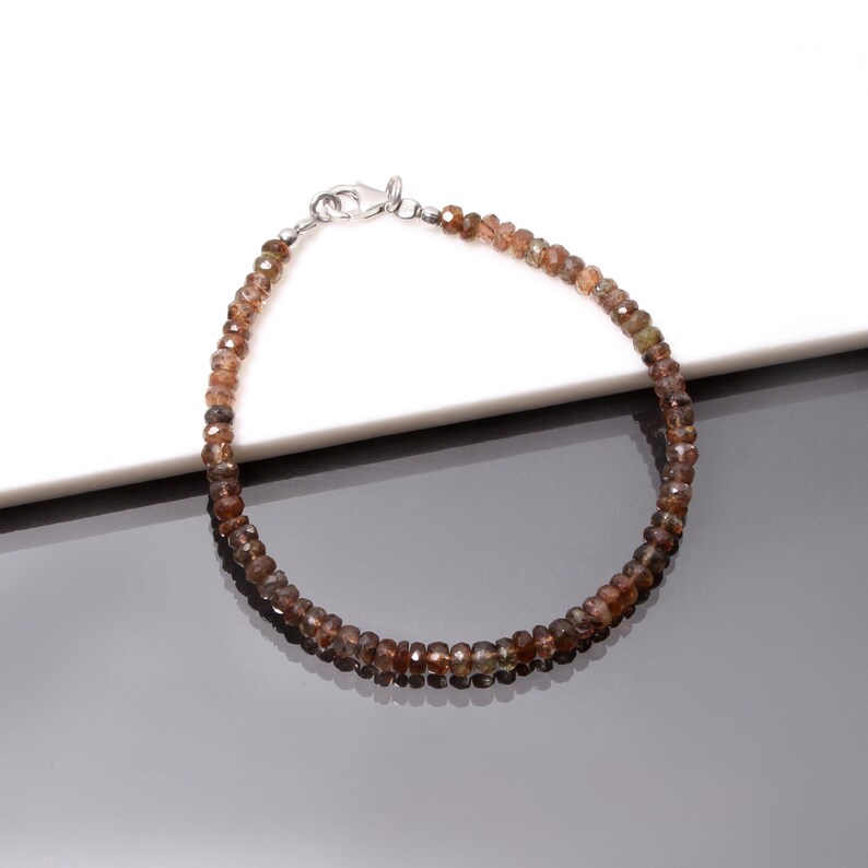 May include: A brown gemstone beaded bracelet with a silver clasp.