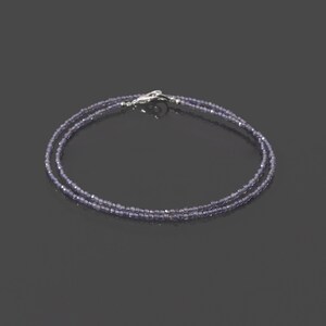 May include: A delicate double strand necklace made with small, faceted amethyst beads. The necklace is secured with a silver clasp.