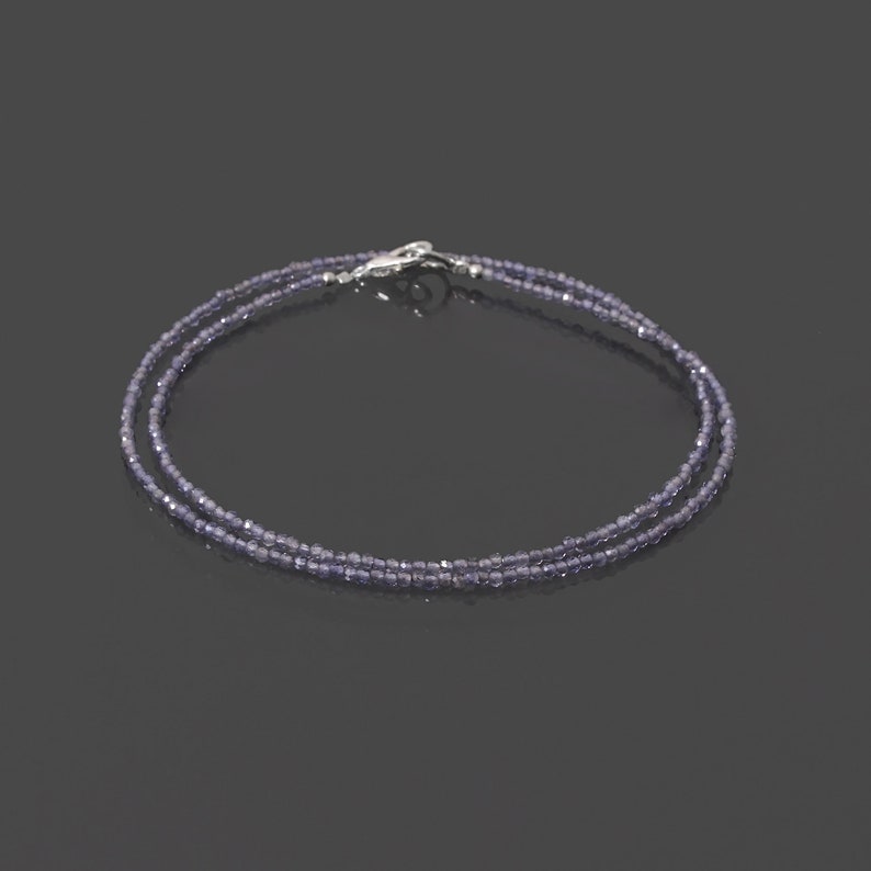 May include: A delicate double strand necklace made with small, faceted amethyst beads. The necklace is secured with a silver clasp.