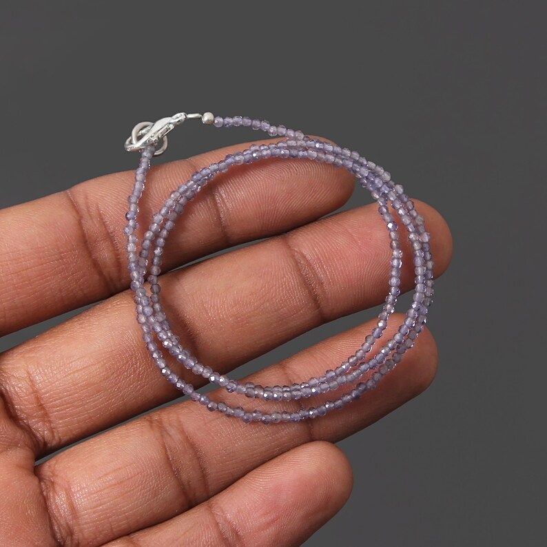 May include: A delicate necklace made with small, faceted amethyst beads. The necklace is silver toned and has a lobster clasp closure.