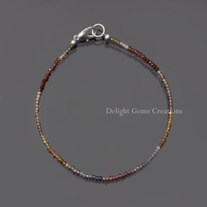 Op de afbeelding: Een delicate armband gemaakt met kleine, gefacetteerde edelstenen in tinten bruin, paars en grijs. De armband heeft een zilveren sluiting.