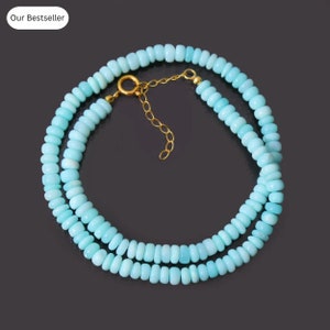 May include: A light blue opal beaded necklace with a gold clasp. The necklace is layered and has a delicate chain.