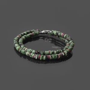 Puede incluir: Un collar de doble cadena hecho de cuentas de piedras preciosas verdes, rosas y negras. Las cuentas son redondas y tienen un acabado liso y pulido. El collar está asegurado con un cierre de plata.