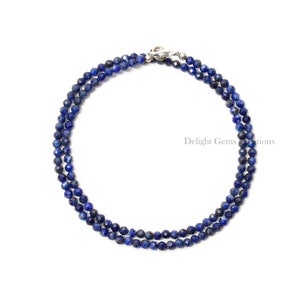 May include: A double strand necklace made of faceted lapis lazuli beads. The necklace is blue and has a silver clasp.