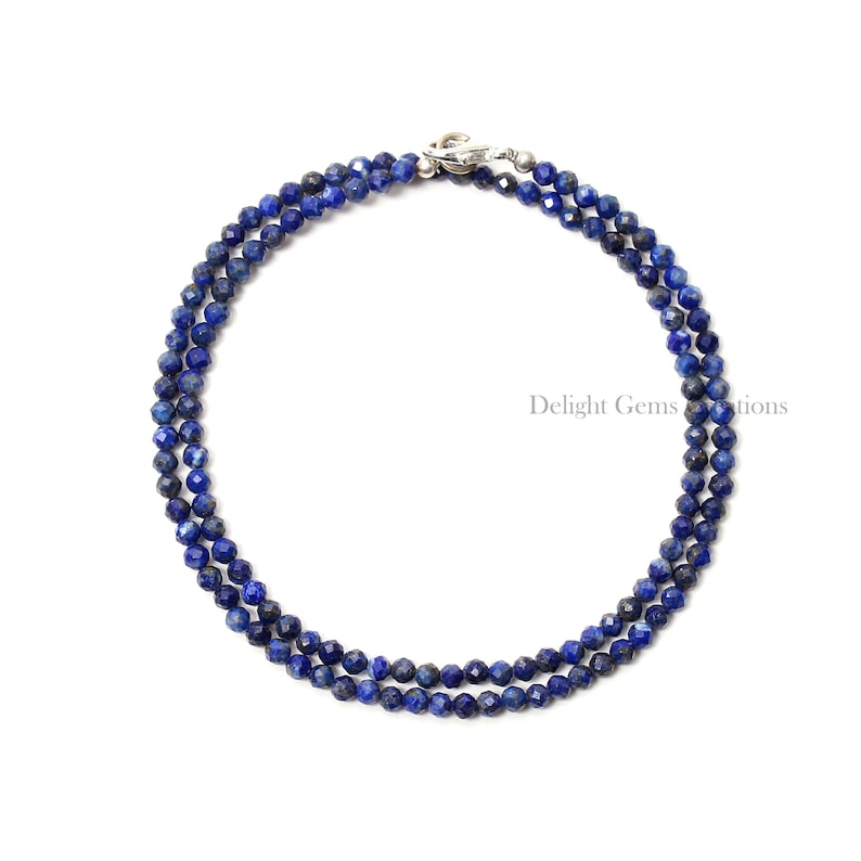 May include: A double strand necklace made of faceted lapis lazuli beads. The necklace is blue and has a silver clasp.