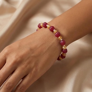 May include: A white ceramic mug with a black handle and the text "But First, Coffee" in a bold, black font. The mug is set against a blurred background, suggesting a cozy setting.