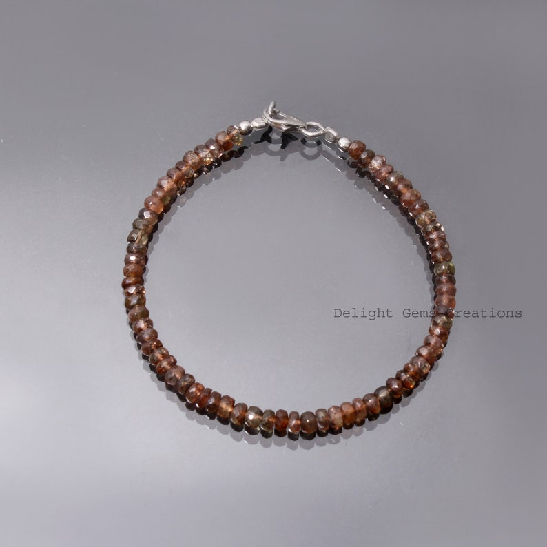 May include: A brown gemstone bracelet with a silver clasp. The bracelet is made of small, round beads.