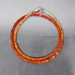 May include: A double strand necklace made of orange, red, and yellow opal beads. The necklace has a silver clasp.