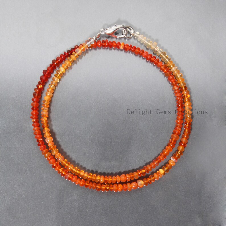 May include: A double strand necklace made of orange, red, and yellow opal beads. The necklace has a silver clasp.