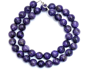 May include: A necklace featuring large, round beads in shades of deep purple with swirling patterns. The beads are strung together with a silver-colored clasp. The necklace is displayed against a white background.
