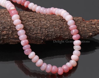 May include: A strand of pink opal beads, strung on a cord, with a natural wood background.  Delight Gems Creations is printed on the wood.