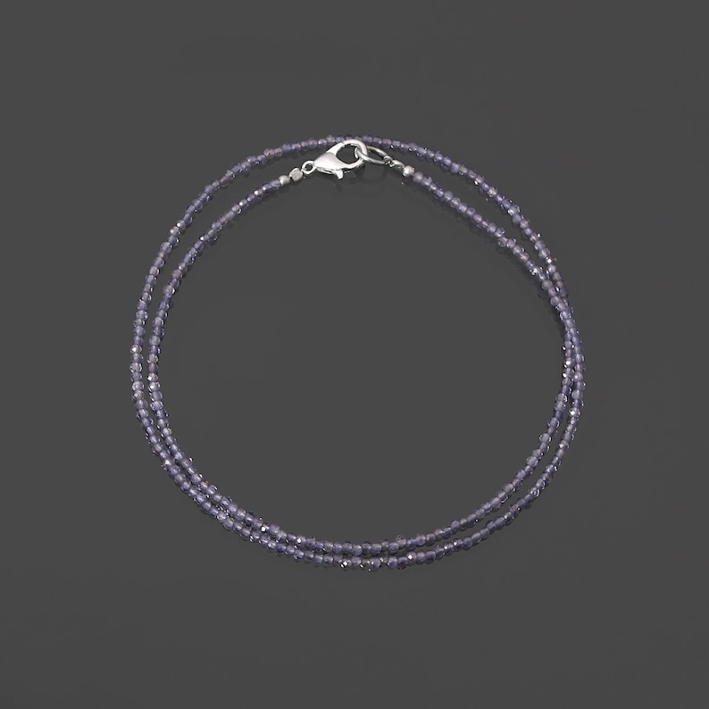 May include: A silver necklace with a double strand of small, light purple beads.