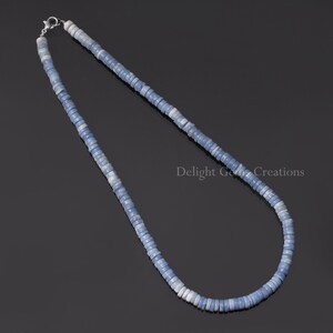 May include: A light blue opal beaded necklace with a silver clasp. The necklace is made of small, round beads that are strung together to create a long, flowing strand.