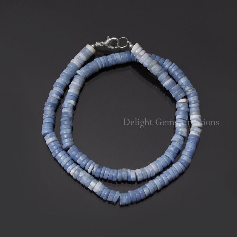 May include: A light blue opal bead necklace with a silver clasp. The necklace is made of many small, round beads that are strung together.