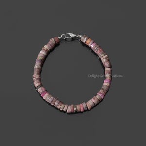 May include: A pink and white gemstone bracelet with a silver clasp. The bracelet is made of small, round beads.